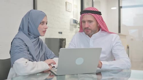 Colleagues Reviewing Laptop in Bright Office