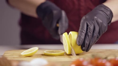 Nahaufnahme eines Küchenchefs, der Zitrone auf einem Holzbrett in dünne Ringe schneidet