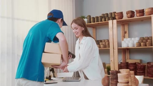 Young woman getting her cardboard box and paying via credit card