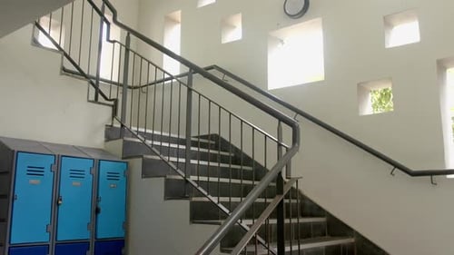 A staircase beside blue lockers in a bright high school corridor