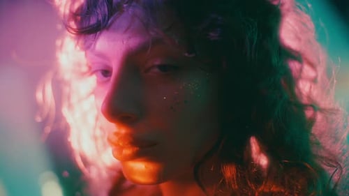 Portrait of Young Attractive Woman with Glitter on Cheek in Neon Light