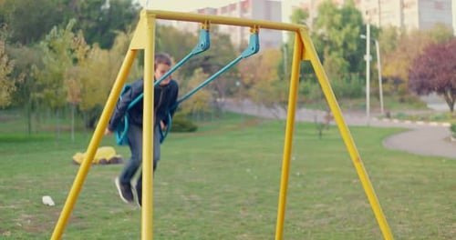 Boy Swinging on Swing Child Having Fun Playing in Outdoor Public Playground