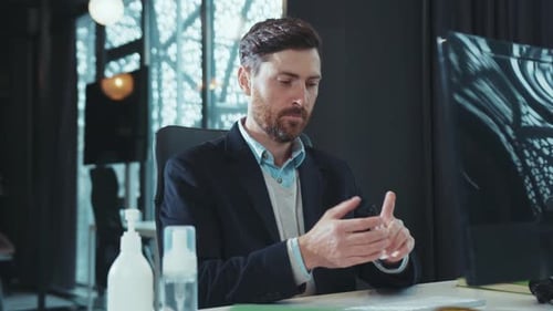 Man Sanitizes Hands at Office Desk