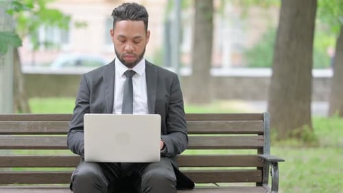 Young Adult Using Laptop on Park Bench