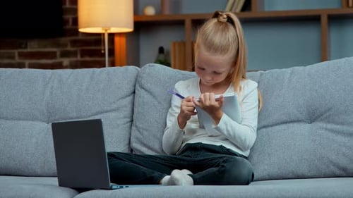 Girl Sits on Couch Doing Homework on Laptop