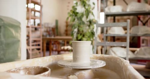 Potter's wheel with clay vase in pottery studio