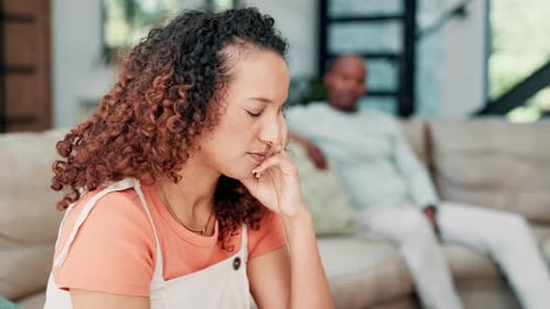 Contemplative Woman Sitting Indoors, Man Relaxing on Sofa