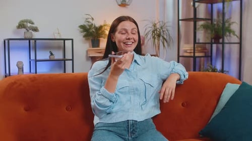 Cheerful woman using voice assistant on phone at home