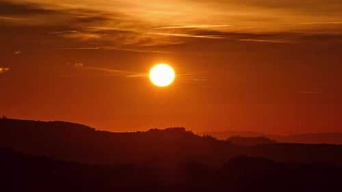 Timelapse of the Sun Setting Over Mountain Ridge with Warm Orange Sky and Fading Light at Dusk