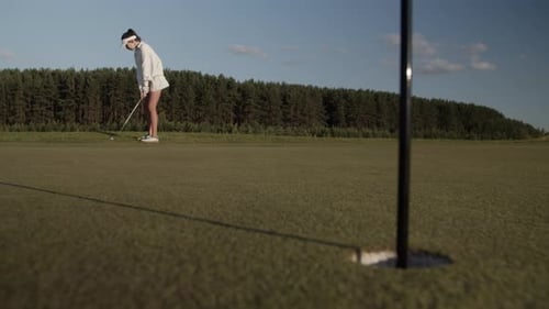Woman Golfer Hits Ball Past Hole with Tag on Luxury Golf Course