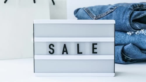 Zoom in Out Light Board with Text SALE with Paper Shopping Bags Jeans Clothes