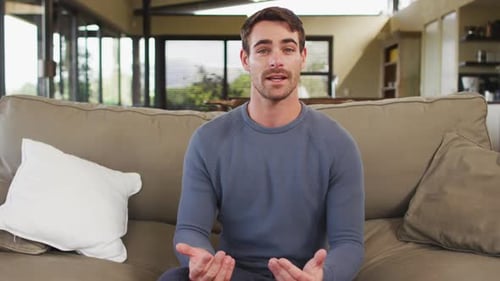 Young Adult Man Talking and Waving on Couch