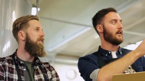 Concepto de fabricación, negocios y personas: hombres con junta trabajando en una cervecería