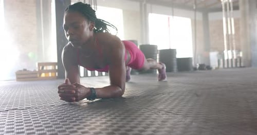 Planking on gym floor, woman in sportswear focusing on core strength workout, copy space