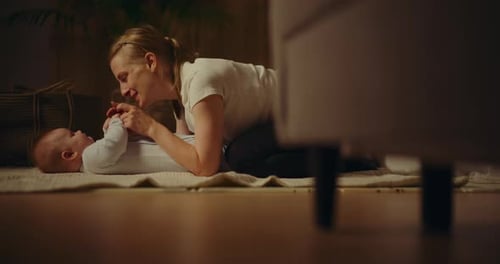 Woman Playfully Interacts with Baby on Floor Indoors