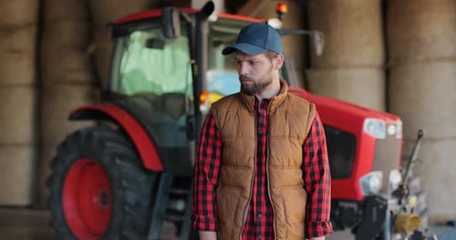 Farmer Stands Proudly By Tractor in Hay Barn