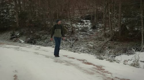 Man in sportswear with backpack walking along snowy footpath in winter forest