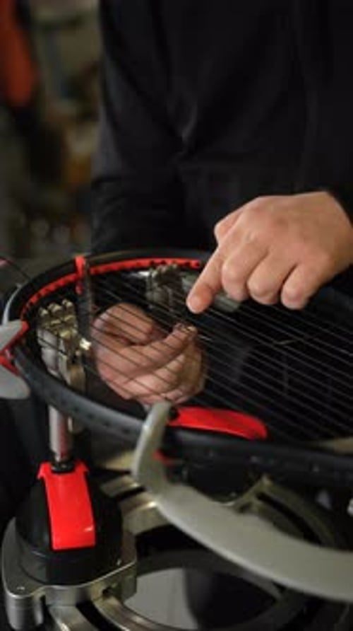 Un technicien de raquette installe les cordes d'une raquette de tennis de manière experte à l'aide d'un équipement de pointe