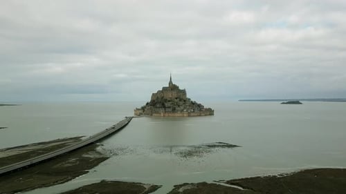 Mont Saint Michel during low tide on cloudy day, Normandy in France. Aerial backward and sky for cop