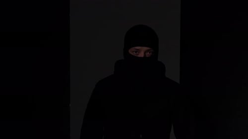 Man in Balaclava Holds Flashlight in the Dark