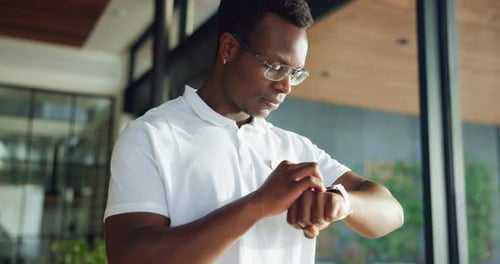 Focused Man Interacts with Smartwatch Indoors During the Day