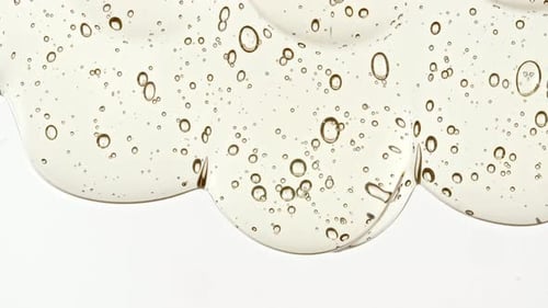 Gel cosmétique fluide transparent avec des bulles de molécules s'écoulant sur la surface blanche
