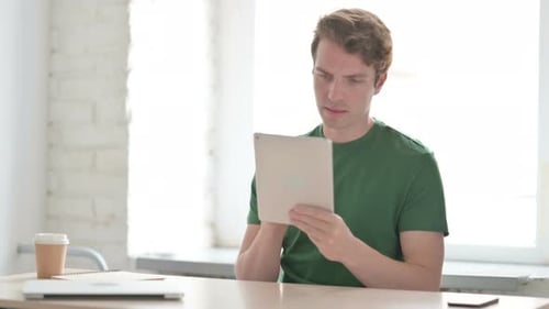 Man Using Tablet at Desk in Bright Office