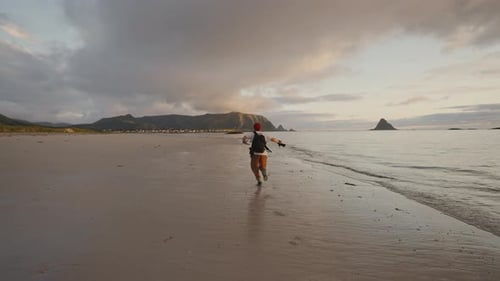Fotógrafo profesional divirtiéndose y corriendo por la costa noruega