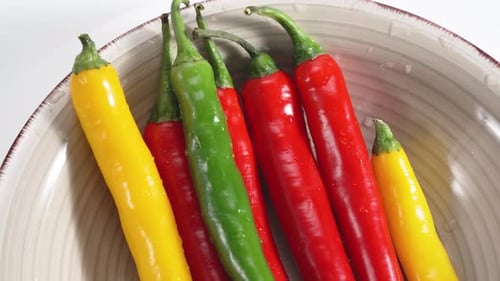 Colorful chili peppers in bowl, close up shot
