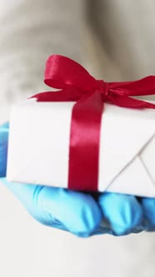 Hand Wearing Glove Holds Wrapped Birthday Gift