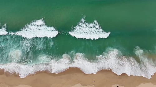 A Breathtaking Aerial View Showcasing the Vibrant Turquoise Waves Crashing Onto Golden Beach Sand