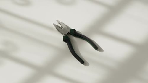 Hand Picking Up Pliers from a White Surface