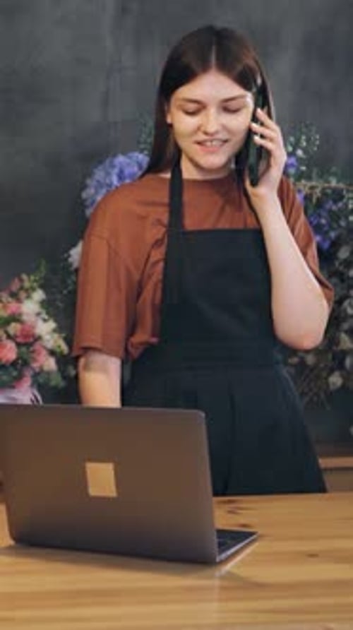 Small Business Owner Cute Female Florist Making a Call to a Flower Greenhouse to Order a Wholesale