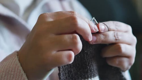 Close Up of Hands Knitting Brown and White Yarn