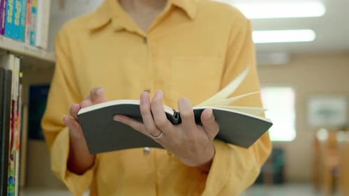 Junger Mann liest ein Buch in einer öffentlichen Bibliothek, blättert um, recherchiert