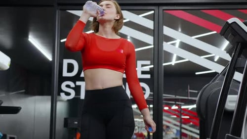 Woman Drinks Water Bottle at the Gym