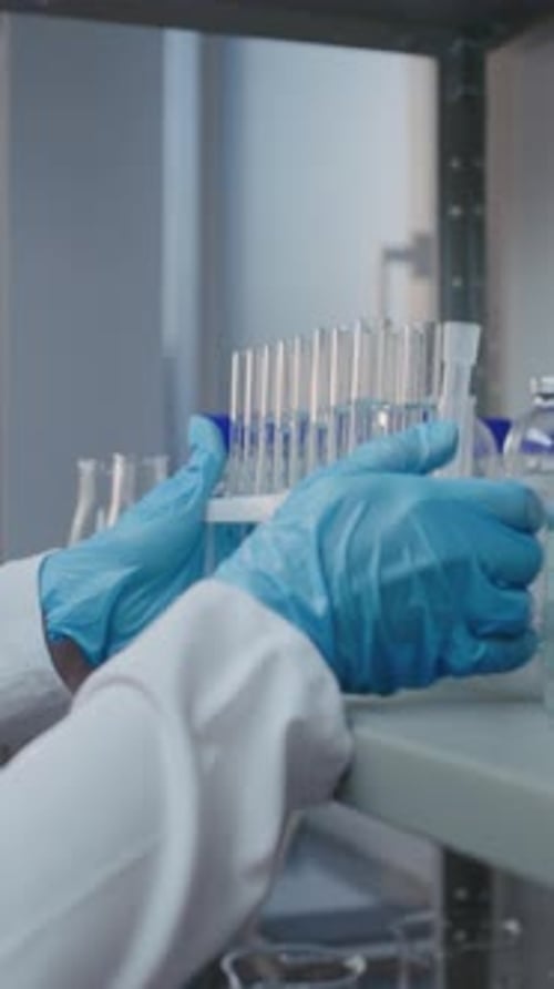 Une chimiste d'un laboratoire de sciences médicales en blouse blanche sort des tubes à essai de l'étagère