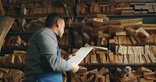 Man Inspecting Wood in a Woodshop