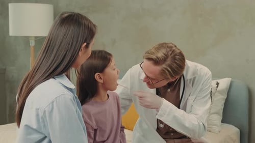 Doctor Examining Child's Throat With Mother Present