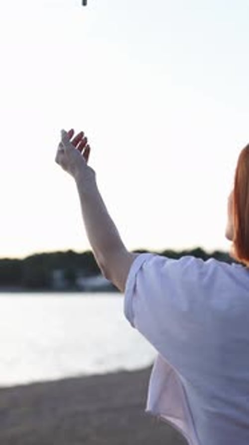 Frau startet bei Sonnenuntergang eine Drohne aus ihrer Hand am Strand