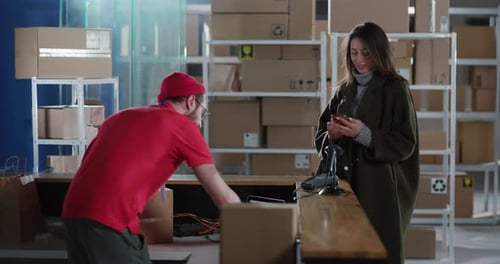 Coupe of Polite Caucasian Worker Giving Parcel Delivery Carton Cardboard Box to Smiling Young Woman
