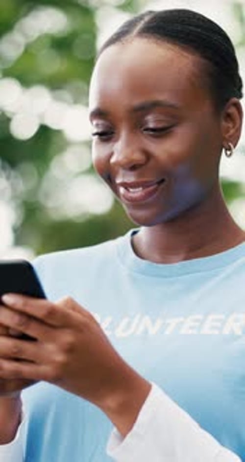 Volunteer, smartphone and black woman in park, smile and program for donation, texting and email