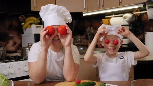 Happy Mother and Son Play with Vegetables in Kitchen