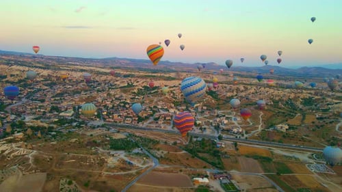 Colorful Hot Air Balloons Flying Over Town at Sunrise