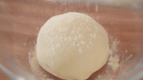 Scatter Flour on Bread Dough in Glass Bowl, Slow Motion Close Up