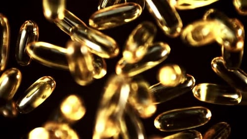 Golden Supplement Capsules Floating on Black Background