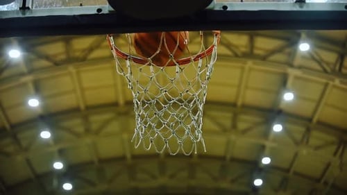 Le basket-ball passe par un cerceau dans une salle de sport