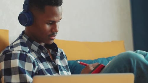 Young Man Studying with Laptop and Headphones Indoors