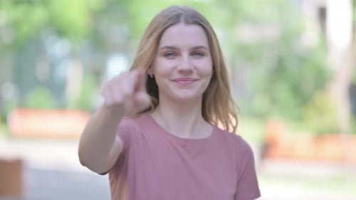 Young Woman Points at Camera with a Smile