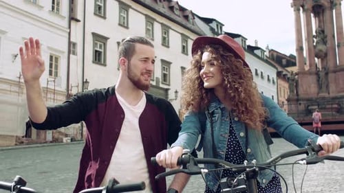 Young couple exploring historic european town streets on electric scooters in summer